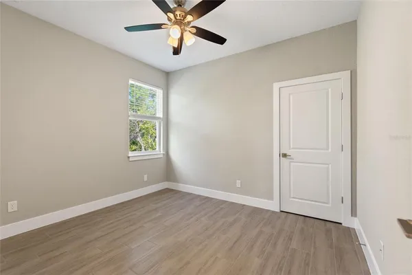 an empty room with wooden floor closet and windows