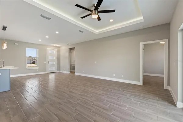 a view of an empty room with wooden floor and a ceiling fan