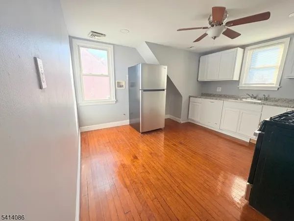 a kitchen with wooden floors and white cabinets