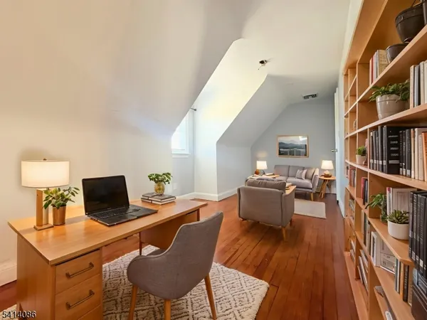 a living room with furniture and a laptop computer sitting on wooden floor