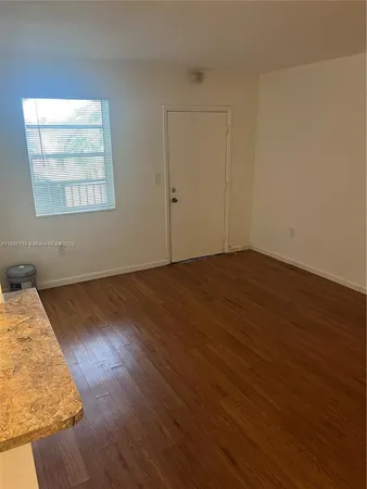 an empty room with wooden floor cabinet and windows