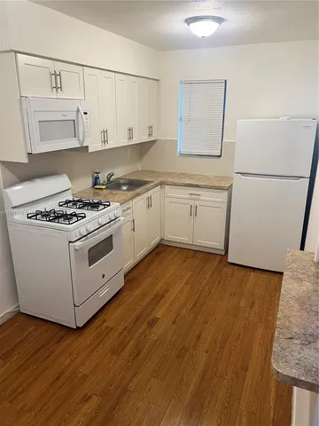 a open kitchen with granite countertop white cabinets and white appliances