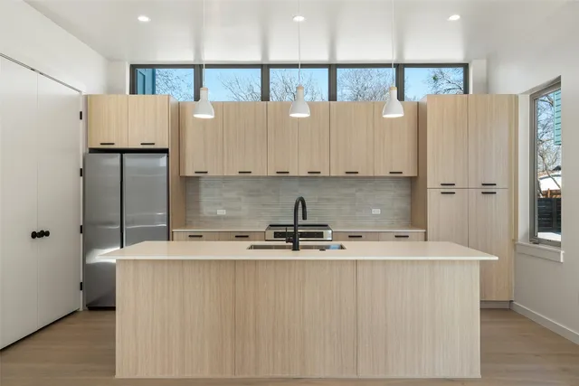a view of kitchen with stainless steel appliances granite countertop a refrigerator a sink and white cabinets