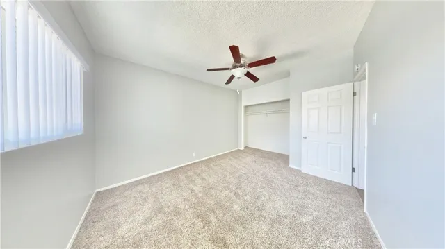 an empty room with a ceiling fan and window
