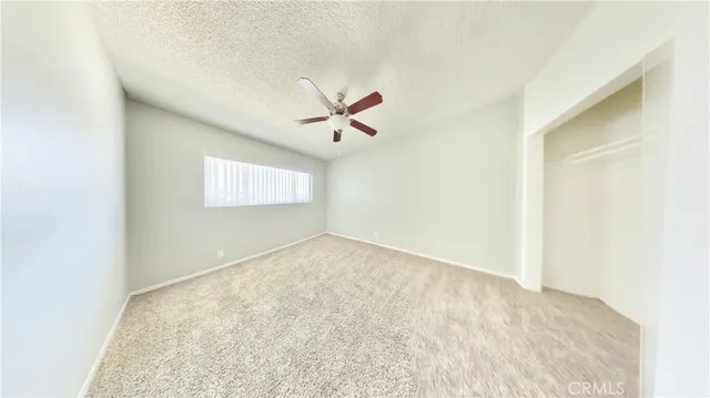 an empty room with ceiling fan and window