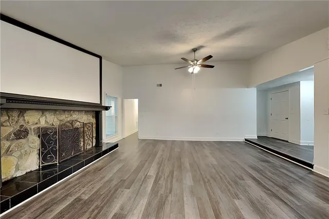 a view of an empty room with wooden floor and a ceiling fan