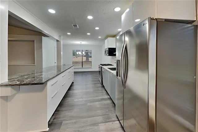 a large kitchen with granite countertop a refrigerator and a sink