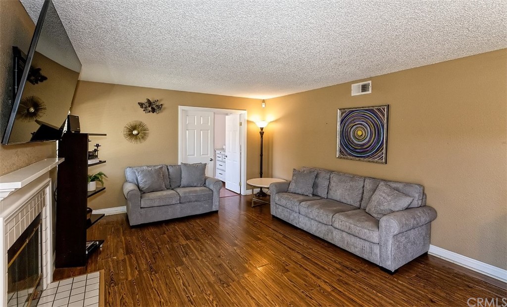10829 Pepper Street Adelanto, CA 92301 - Photo 17 of 48 a living room with couches and a flat screen tv with kitchen view