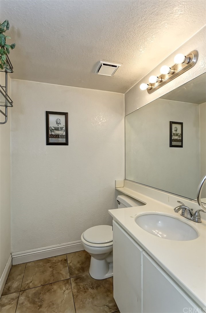 10829 Pepper Street Adelanto, CA 92301 - Photo 23 of 48 a bathroom with a granite countertop toilet a sink and mirror