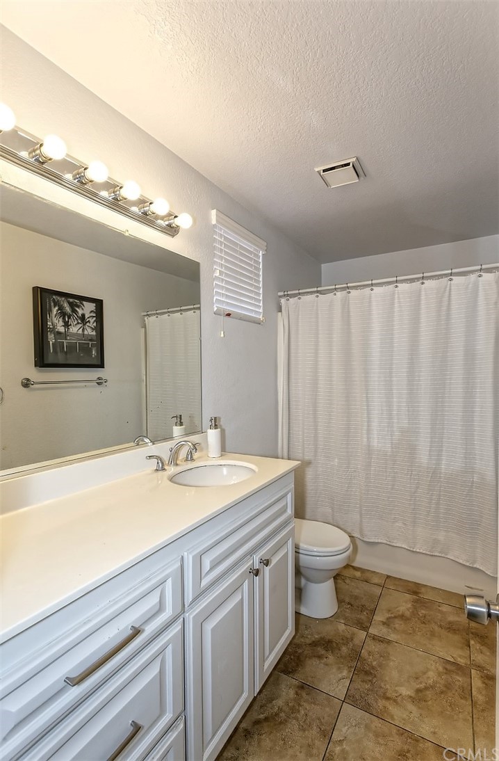 10829 Pepper Street Adelanto, CA 92301 - Photo 31 of 48 a spacious bathroom with a granite countertop sink a toilet a mirror and a shower