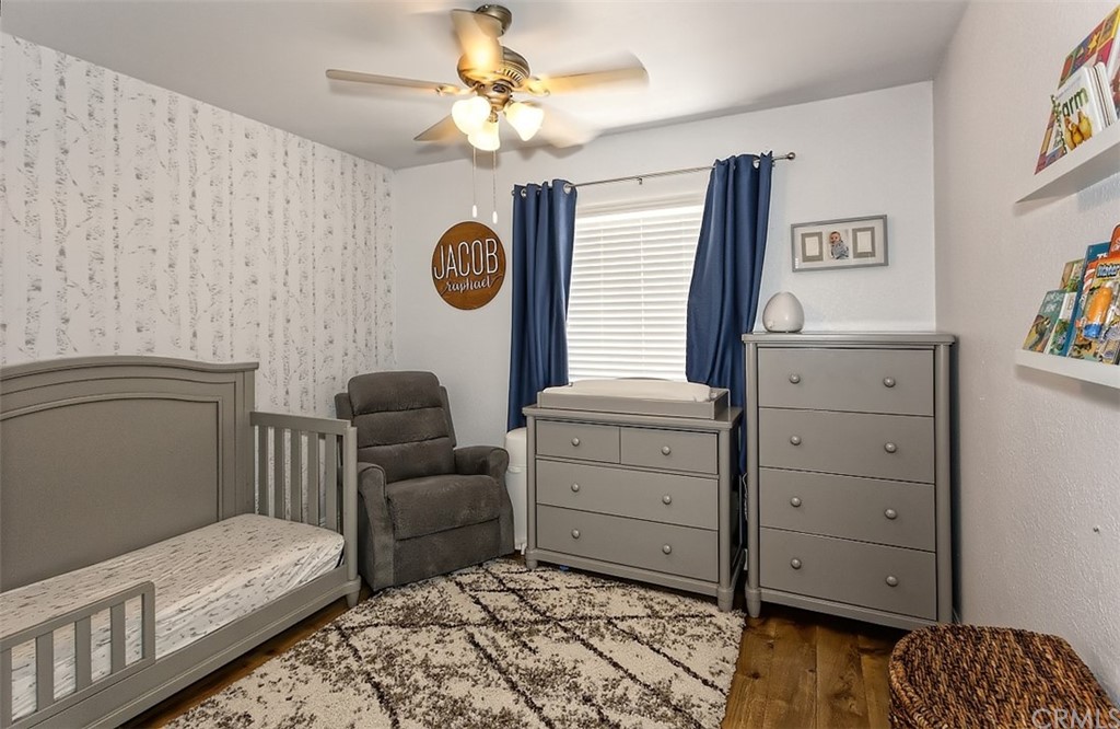 10829 Pepper Street Adelanto, CA 92301 - Photo 32 of 48 a bedroom with a baby bed couch and a window