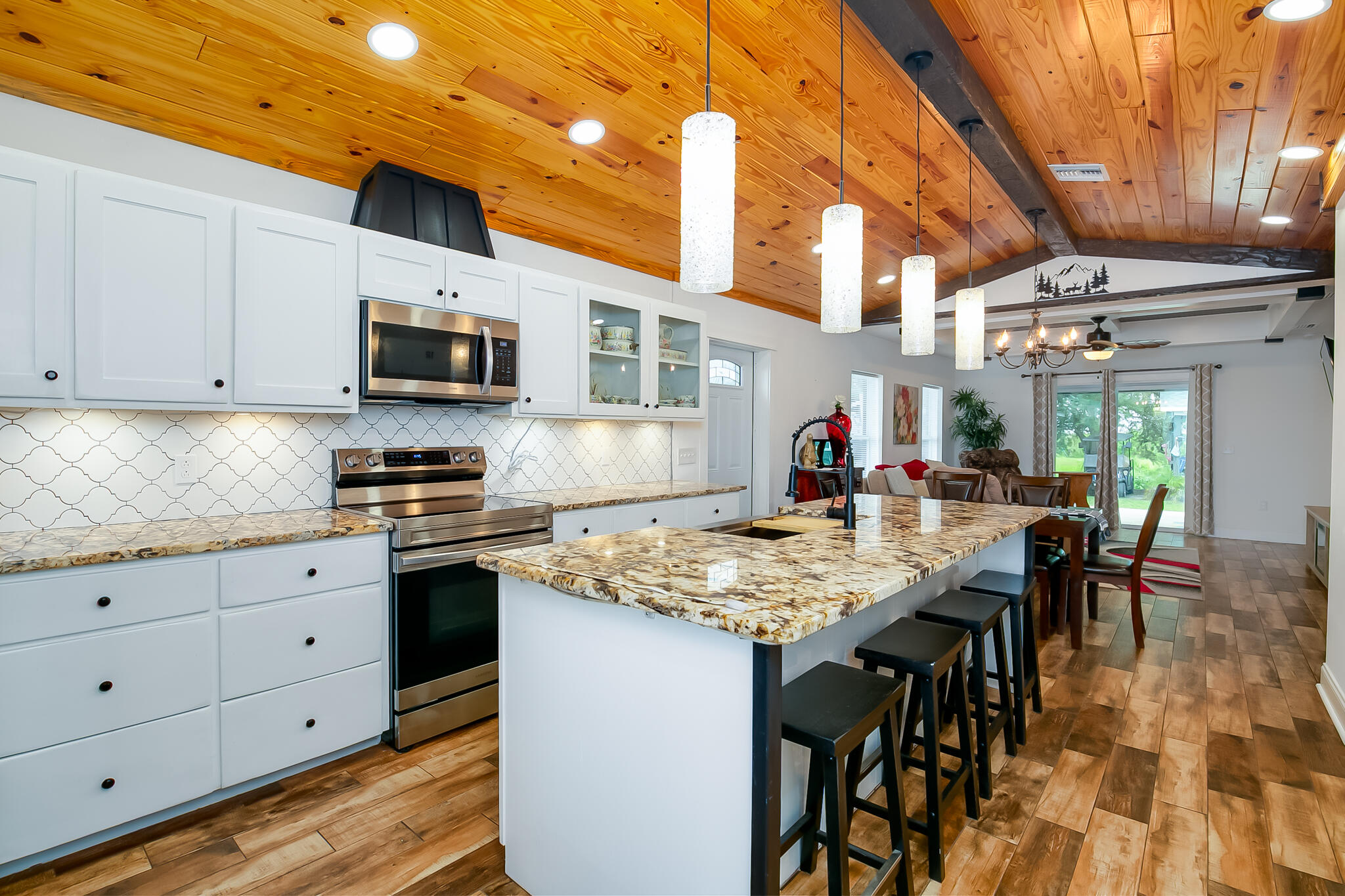 a kitchen with stainless steel appliances granite countertop a stove top oven a sink dishwasher a dining table and chairs with wooden floor