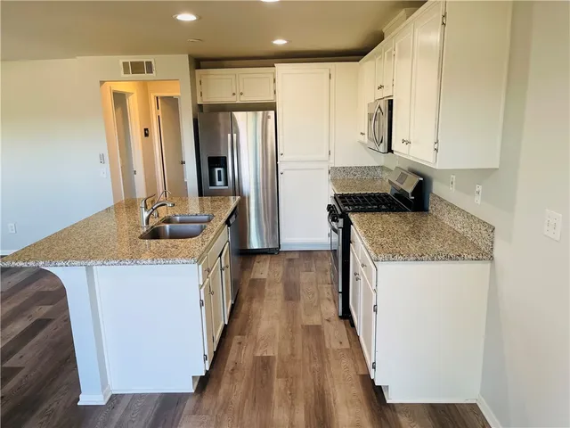 a kitchen with stainless steel appliances granite countertop a refrigerator a stove and a wooden floors