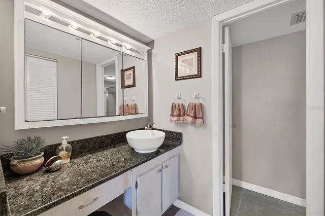 a bathroom with a granite countertop sink and a mirror