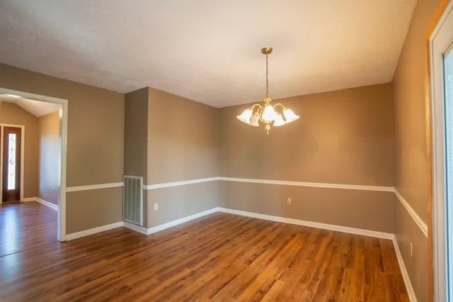 a view of empty room with wooden floor and ceiling fan