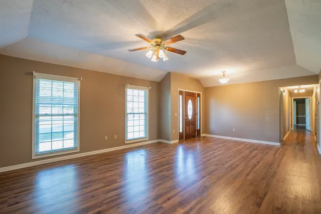 a view of an empty room with window and wooden floor
