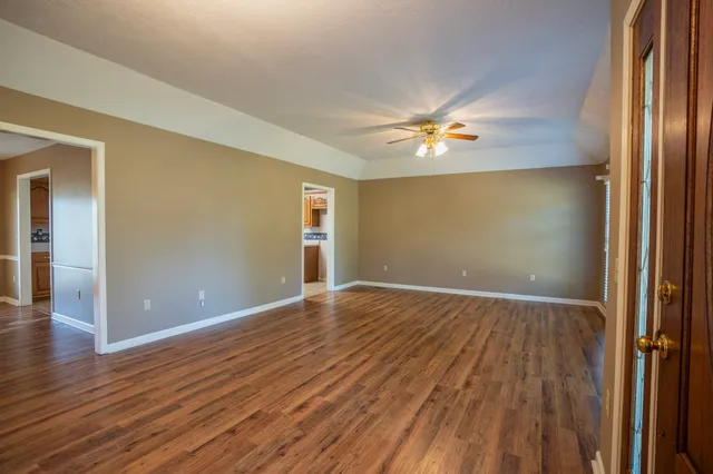 an empty room with wooden floor and a ceiling fan