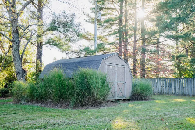 a view of a backyard with large trees and wooden fence