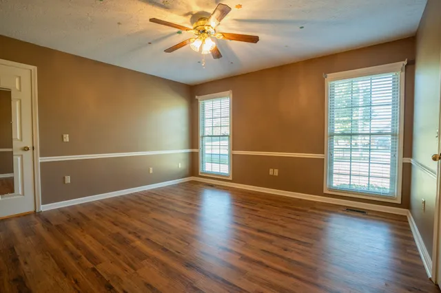 an empty room with wooden floor and windows