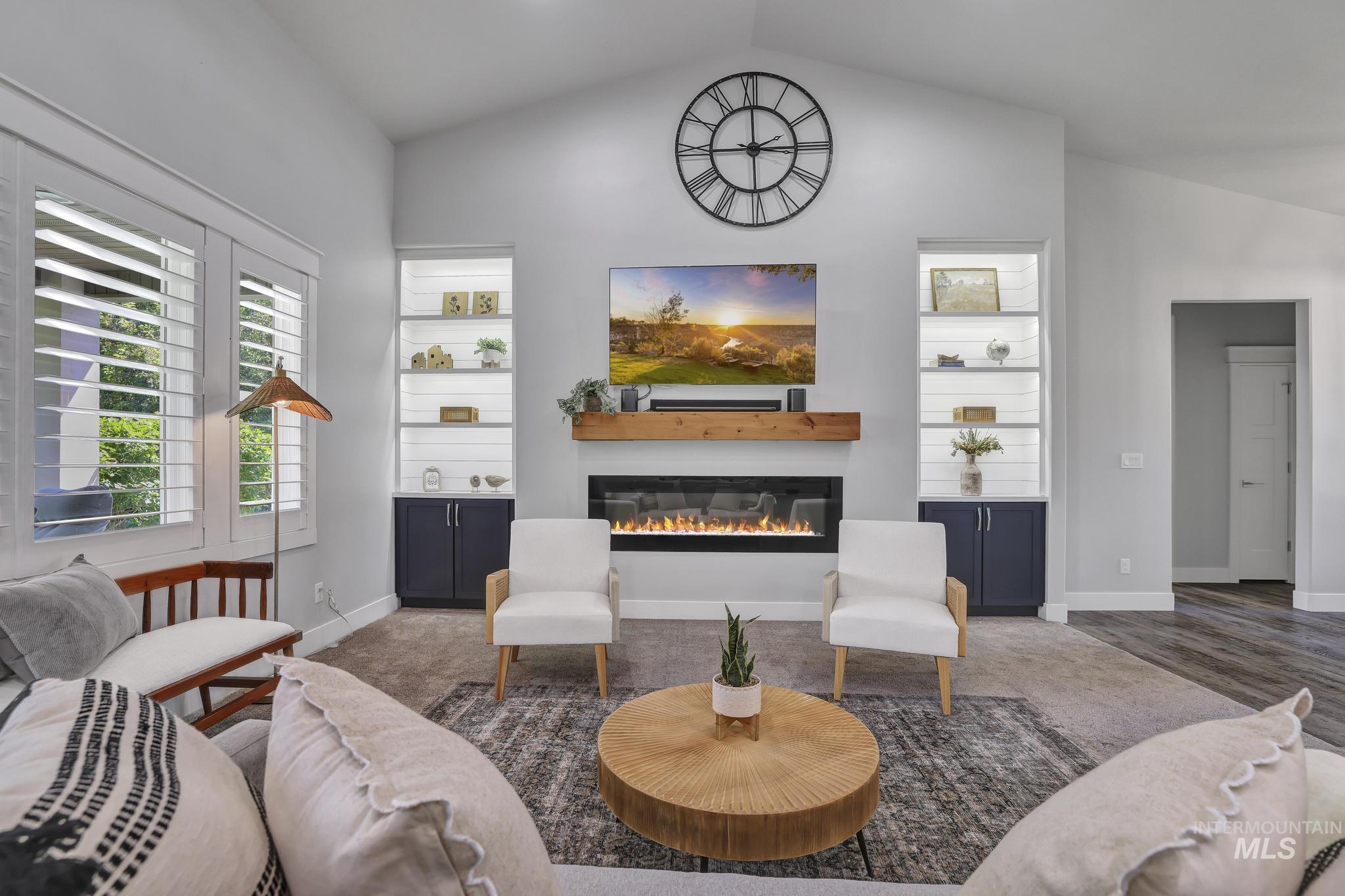 1937 Tamarack Loop Twin Falls, ID 83301 - Photo 11 of 50 Vaulted ceiling living area featuring a linear fireplace with a wood mantel, built-in shelving with accent lighting, plantation shutters, and wood-finish flooring