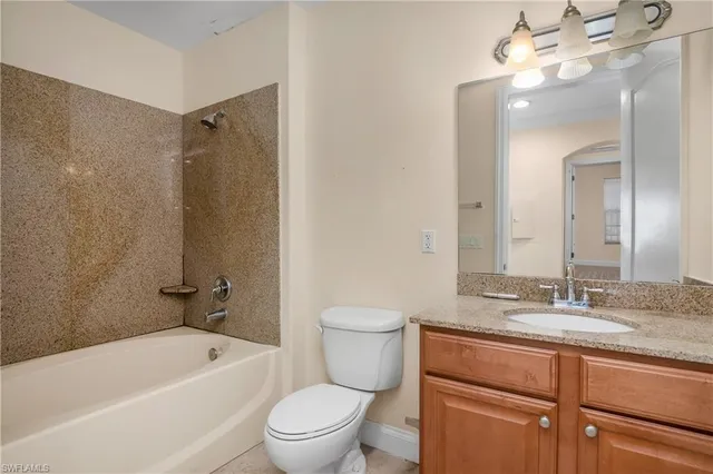 a bathroom with a granite countertop toilet a sink and a bathtub