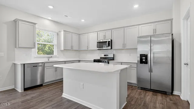 a kitchen with kitchen island white cabinets white stainless steel appliances and wooden floors