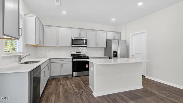 a kitchen with kitchen island granite countertop a sink cabinets and stainless steel appliances