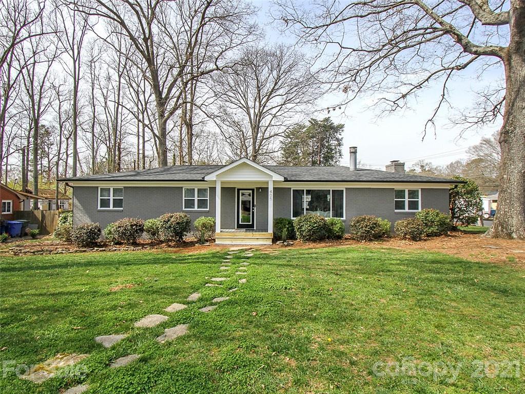 a front view of a house with a garden and trees