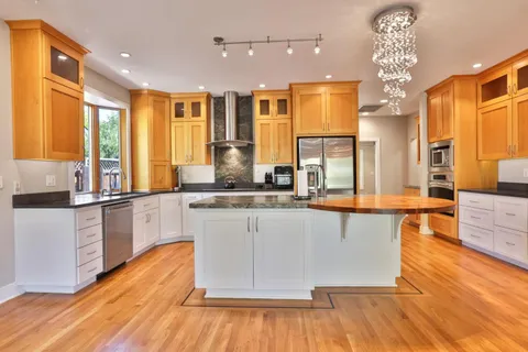 a large kitchen with granite countertop a large counter top space a sink stainless steel appliances and cabinets
