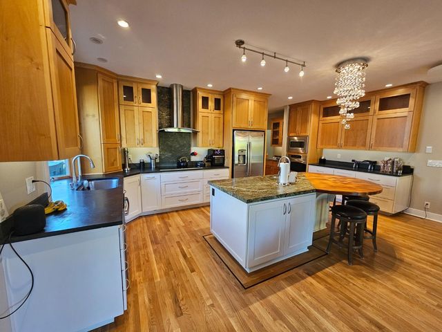 a living room with stainless steel appliances kitchen island granite countertop furniture and a wooden floor