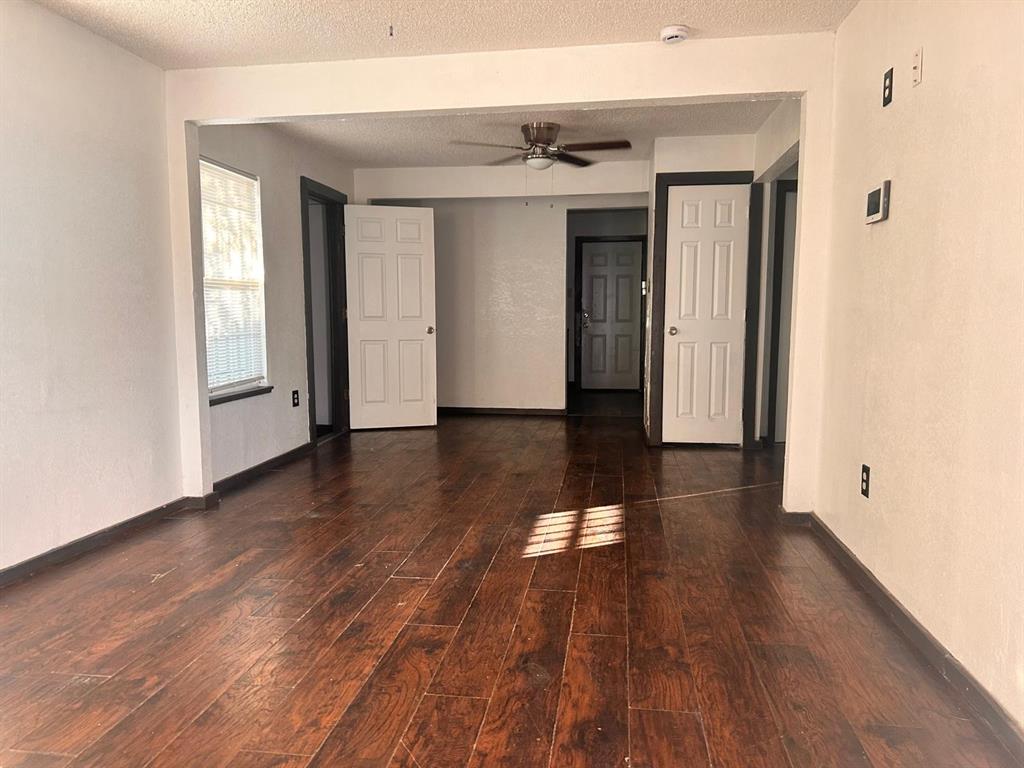 2710 Mitchell Street Dallas, TX 75210 - Photo 2 of 15 Empty room with dark wood-type flooring, a textured ceiling, ceiling fan, and a textured wall