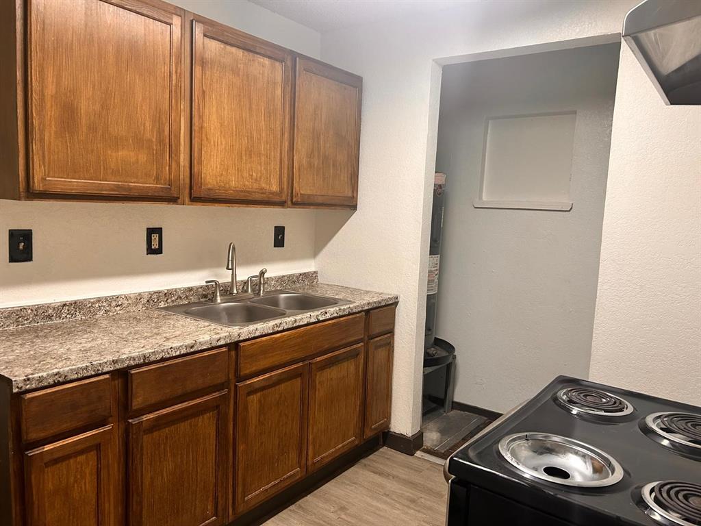 2710 Mitchell Street Dallas, TX 75210 - Photo 5 of 15 Kitchen with black / electric stove, light wood finished floors, extractor fan, light countertops, and brown cabinetry