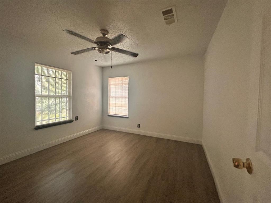2710 Mitchell Street Dallas, TX 75210 - Photo 9 of 15 Unfurnished room featuring a textured ceiling, healthy amount of natural light, dark wood-type flooring, and ceiling fan