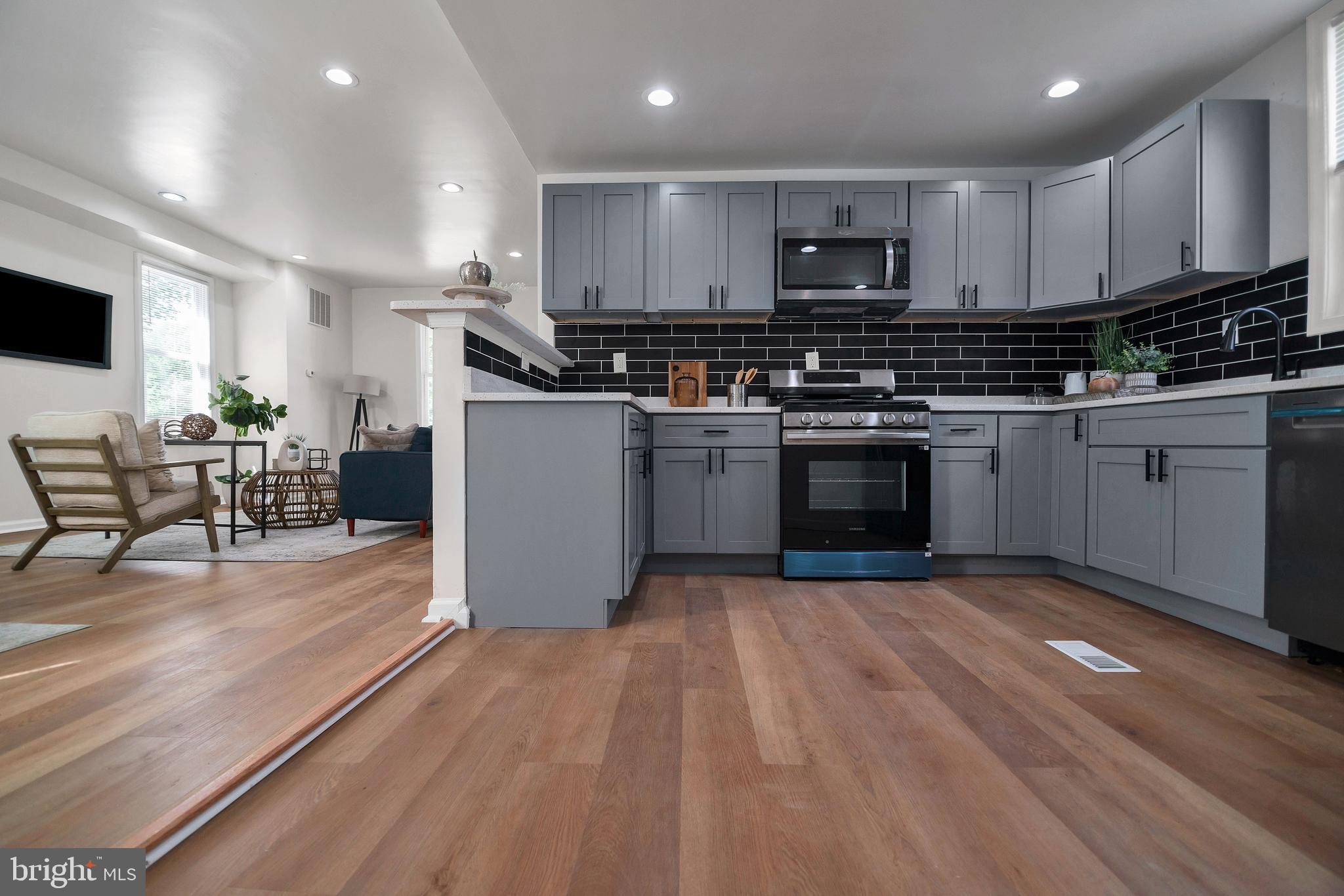 4132 Marx Avenue Baltimore, MD 21206 - Photo 23 of 76 a kitchen with granite countertop a stove top oven a sink dishwasher a dining table and chairs with wooden floor