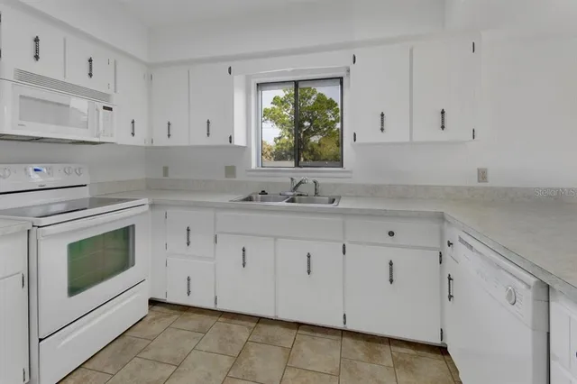 a kitchen with granite countertop white cabinets white appliances and a sink