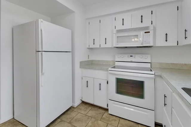 a kitchen with white cabinets white stainless steel appliances and sink