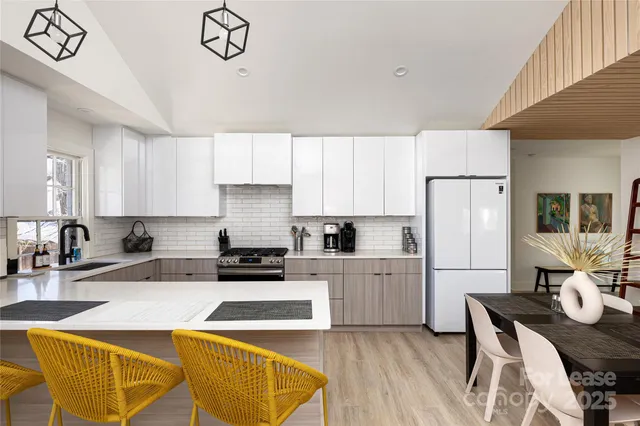 a kitchen with stainless steel appliances granite countertop a refrigerator a stove a sink dishwasher and white cabinets with wooden floor