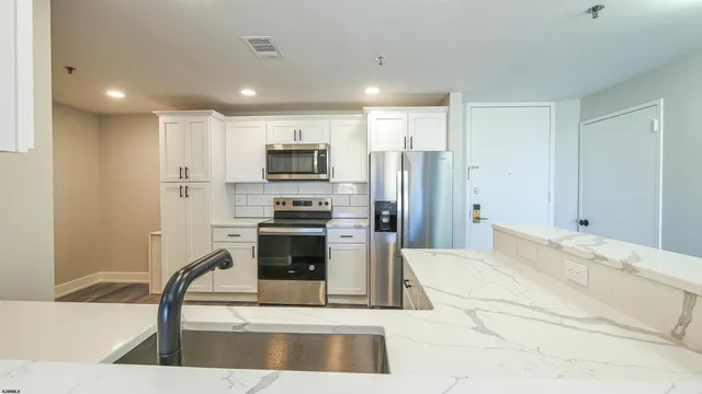 a kitchen with stainless steel appliances kitchen island granite countertop a refrigerator and a sink