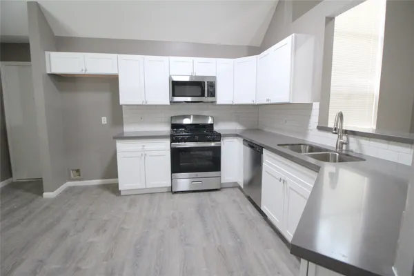 a kitchen with stainless steel appliances granite countertop a stove a sink and a microwave