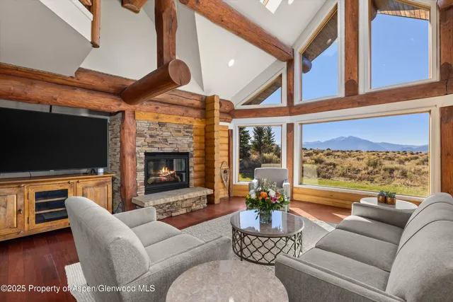 a living room with furniture a fireplace and a floor to ceiling window