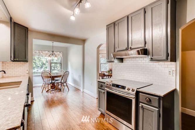 832 Southwest 4th Place Renton, WA 98057 - Photo 3 of 25 a kitchen with stainless steel appliances granite countertop a stove top oven a sink a dining table and chairs with wooden floor