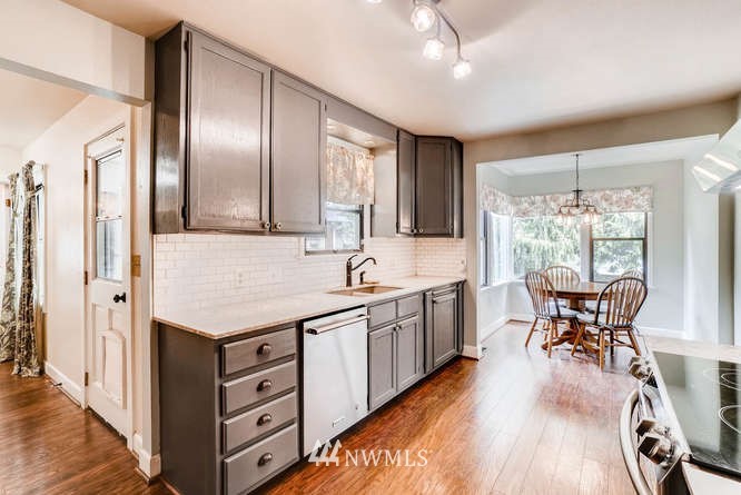 832 Southwest 4th Place Renton, WA 98057 - Photo 4 of 25 a kitchen with granite countertop a sink appliances dining table and chairs