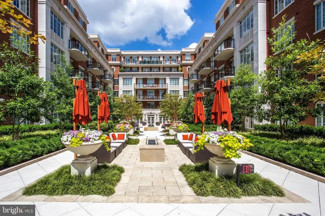 a group of people sitting on a sidewalk in front of a building