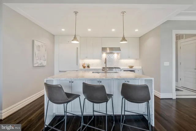 a large white kitchen with a dining table chairs and wooden floor