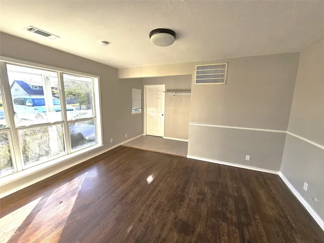 an empty room with wooden floor and windows