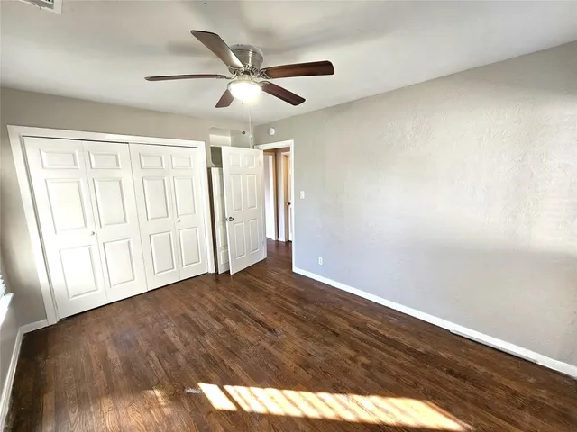 an empty room with wooden floor fan and windows