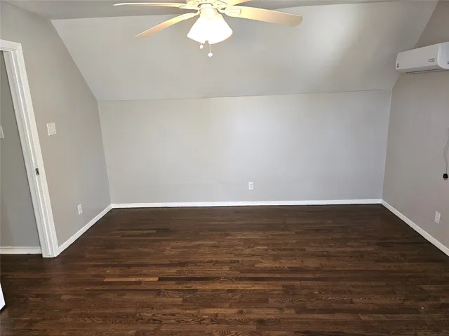 a view of an empty room with wooden floor and a ceiling fan