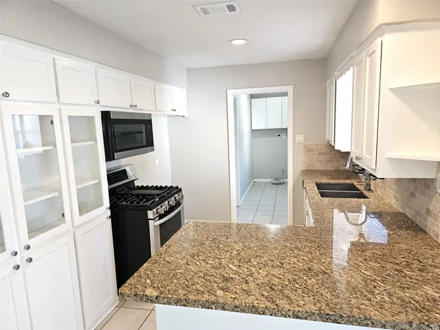 a kitchen with granite countertop a refrigerator stove and sink