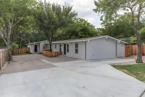 a view of a house with a yard and large tree