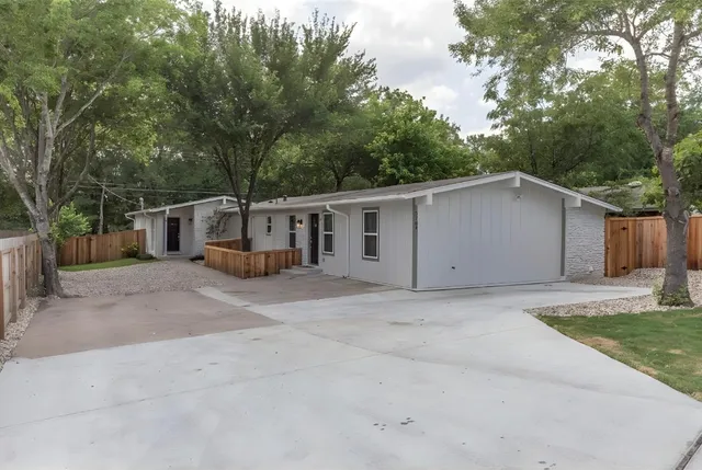 a view of a house with a yard and large tree